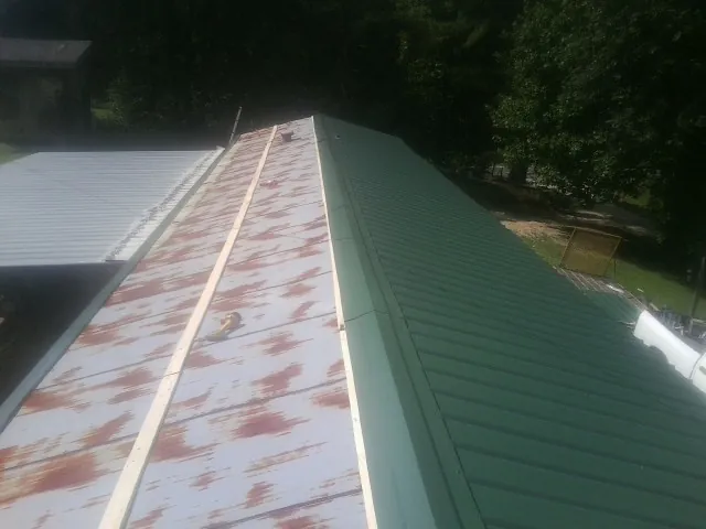 Old rusted panels beside newly installed green metal roofing — Wind Damage Roof Repair by Roofing Brothers in Gypsum
