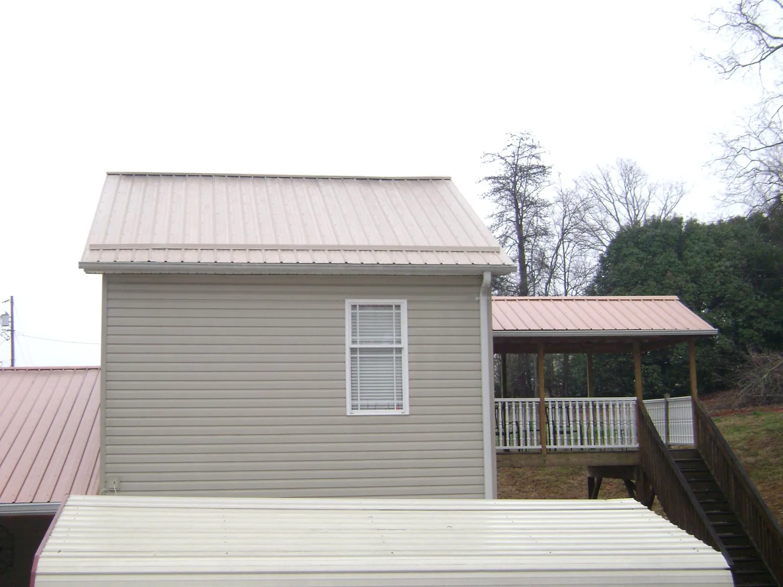 Tan metal roofs on a two story addition and attached porch, from a Roof Replacement job in Gypsum